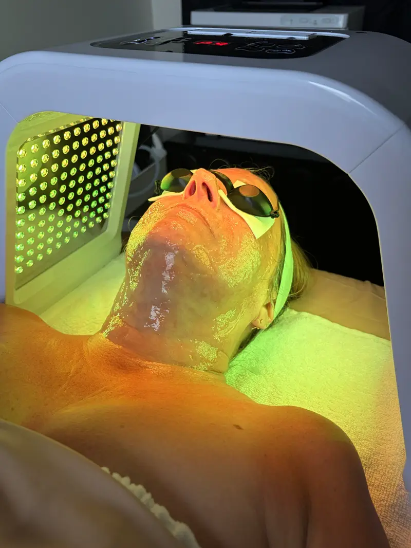 Client relaxing under green LED light therapy with protective eye shields
